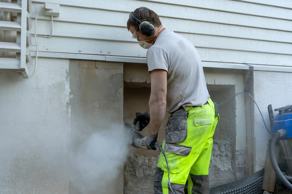 A construction worker using a drill in a concrete wall
